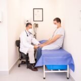 Trusă de prim ajutor deschisă pe o masă, cu bandaje, comprese sterile, foarfece și termometru